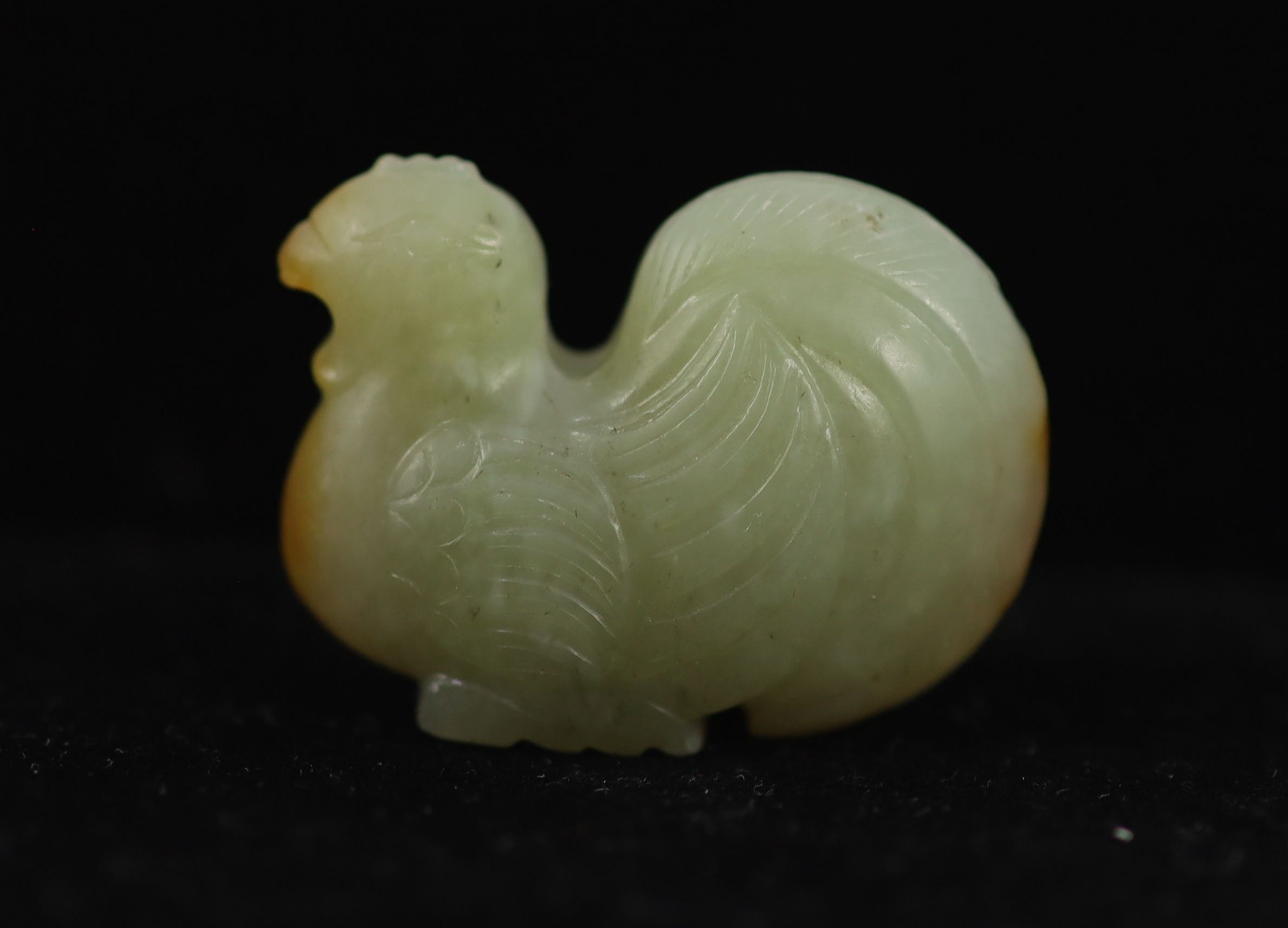 A Chinese pale celadon and russet jade ‘cockerel’ finial, 3.6 cm